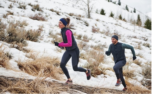 Two runners ascend a snowy hill in the holiday season.