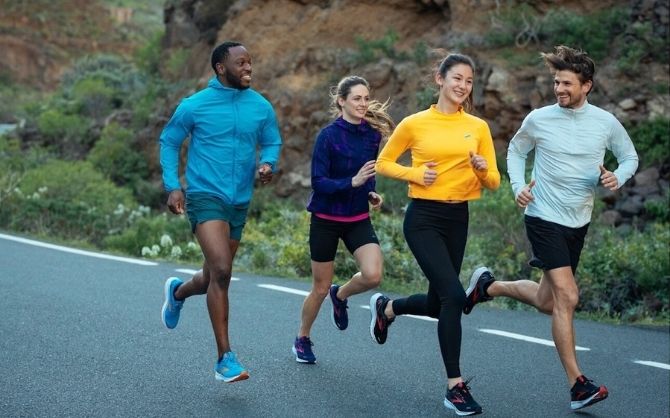 A group of four runners laugh together during a group run.
