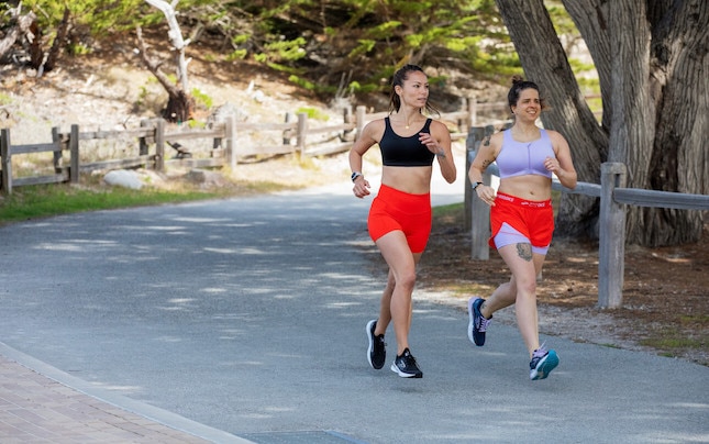 Twee vrouwen die hardlopen op een verhard voetpad