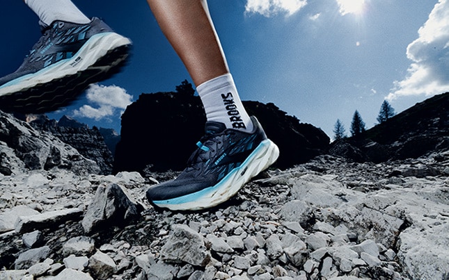 Close-up of someone running in the Cascadia 19 trail running shoes on a rocky terrain
