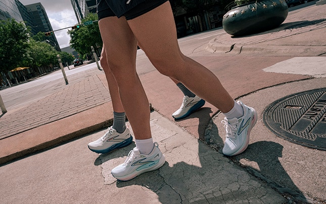 Primo piano dei piedi di due persone che camminano su un marciapiede indossando Glycerin 22 di Brooks