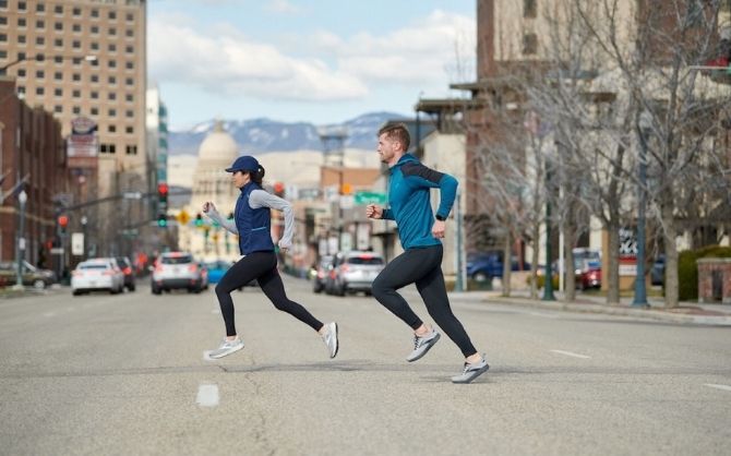 Two runners run across a city street.