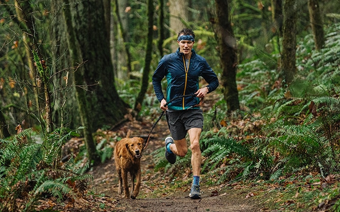Homme courant avec son chien dans la forêt.