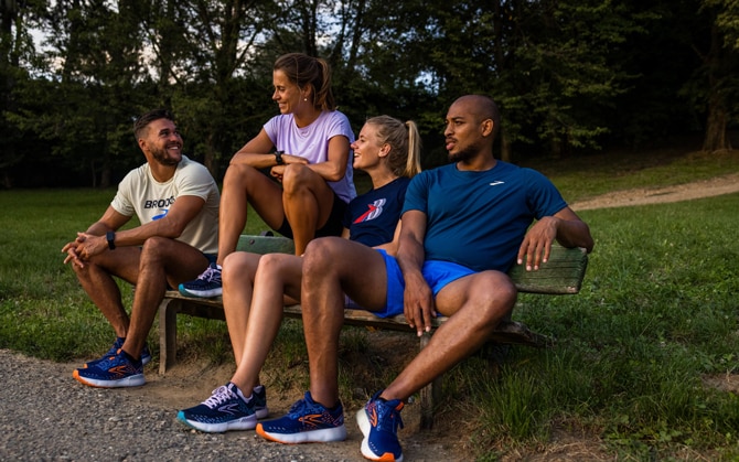 A runner stretches and laughs with two fellow runners