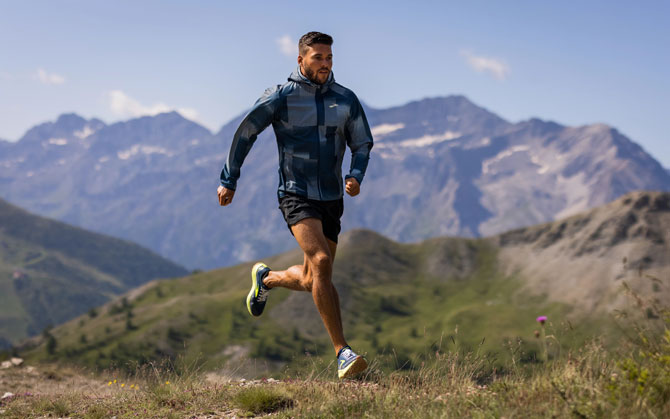 A runner leaps over rocky terrain on a trail run.
