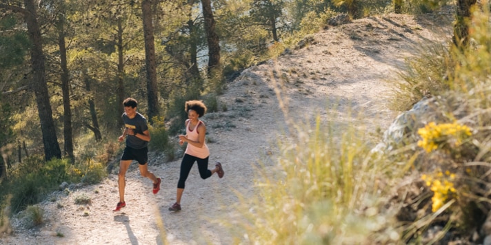 Twee hardlopers lopen samen een duurloop door een bebost gebied.