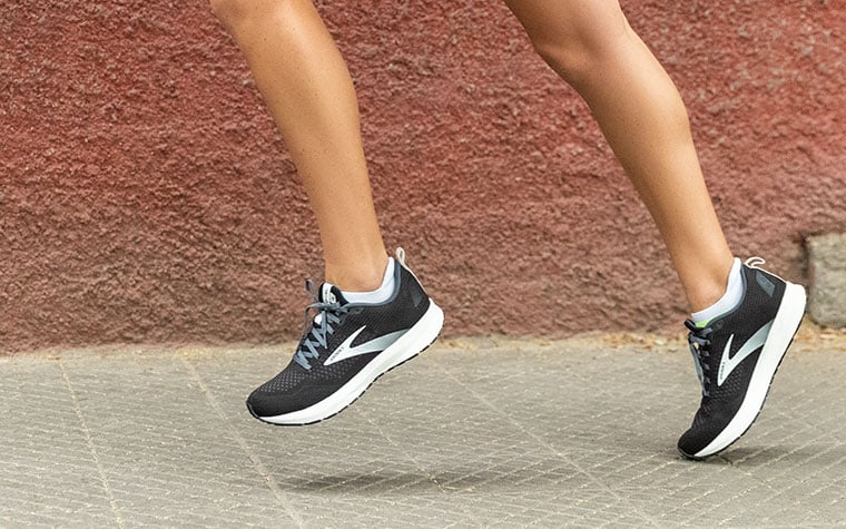 Un coureur s’élance avec des chaussures Revel noires et blanches.