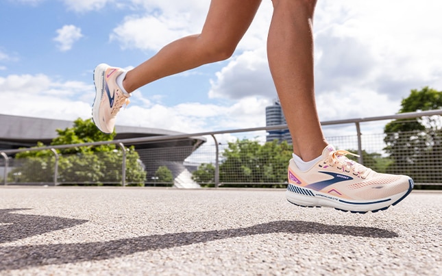 Jambes d’une runneuse en train de courir sur du bitume dans un environnement urbain