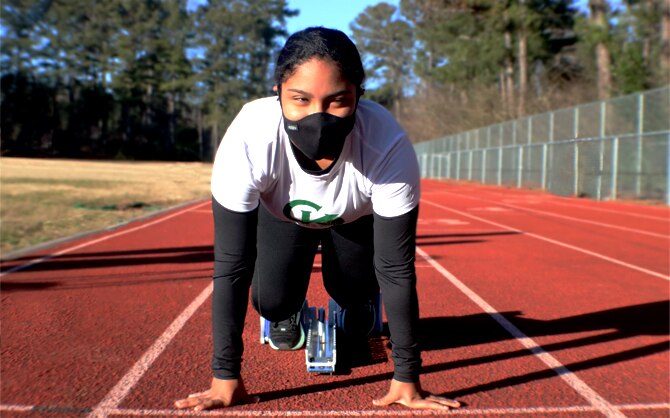 Women on a track with her feet in race blocks