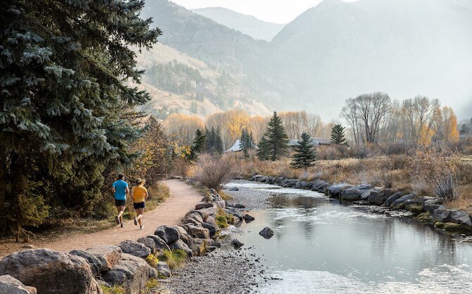 Two runners on a trail next to a river