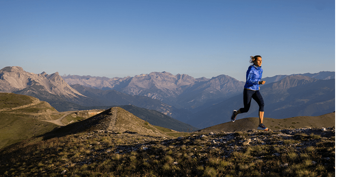 Eine Frau läuft auf einem Trail in den Bergen