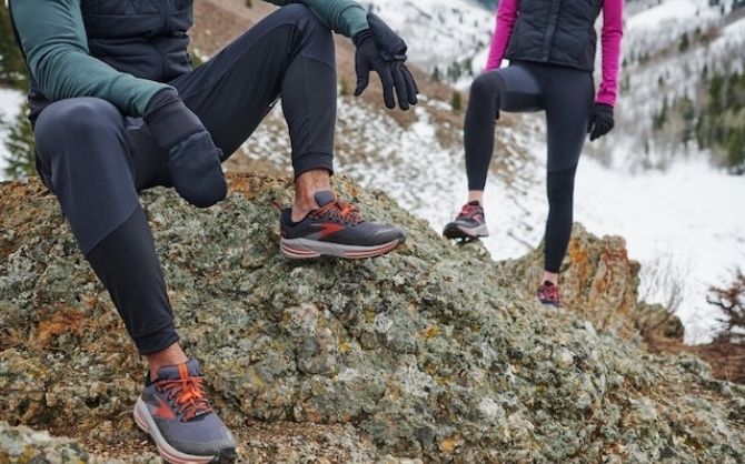 Two runners wearing running pants take a break on a trail run.