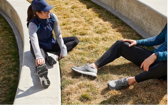 Two runners sit on the ground and recover after a marathon race.