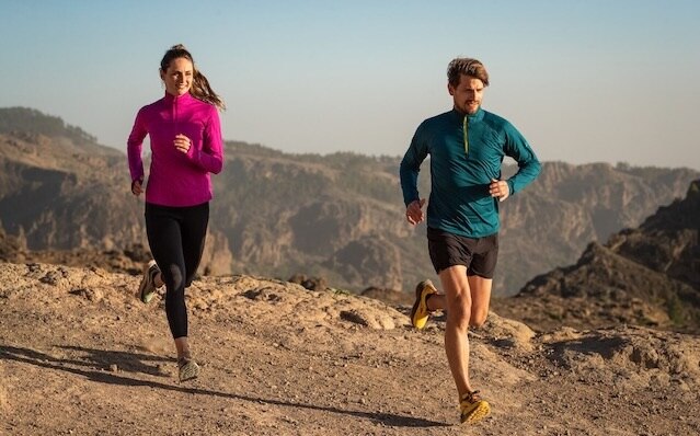 Two runners on a trail run in the mountains