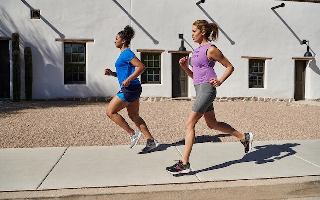 Two runners on a sidewalk.