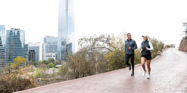 Zwei Läufer begeben sich zusammen auf einen Lauf auf einem Pfad außerhalb einer Stadt.