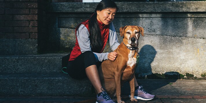 Eine Frau sitzt mit ihrem Hund nach einem Lauf.