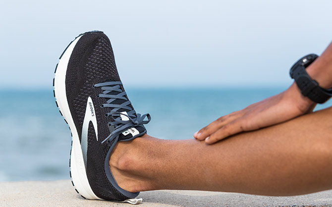 Close-up shot of a runner’s leg in a seated calf stretch position