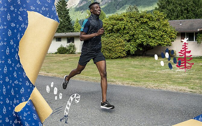 A smiling runner in mid-stride runs on a neighborhood path with houses and mountains in the background. 