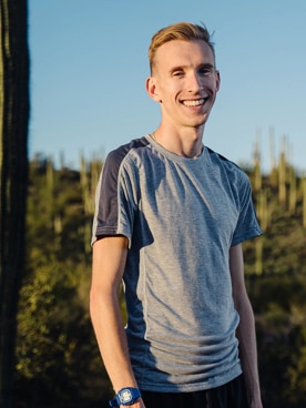 Adam Dalton debout à l’extérieur, souriant