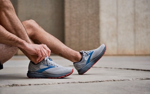 A runner laces up their shoes before a run.