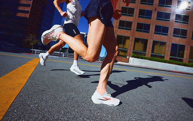 Athletes running through a downtown city street in Brooks performance running shoes.
