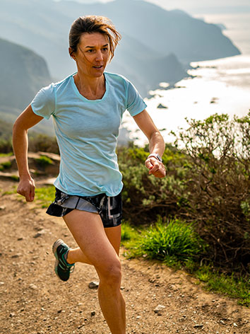 Mujer corriendo por un sendero con vistas del mar