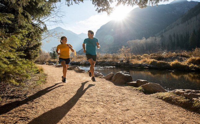 A man and a woman running on trail