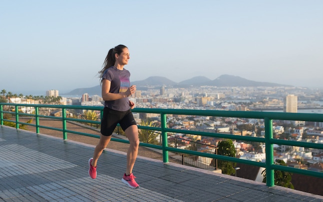 A solo runner on a path overlooking a city
