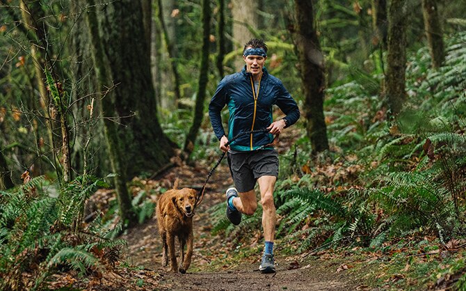 Man running with his dog through the forest.