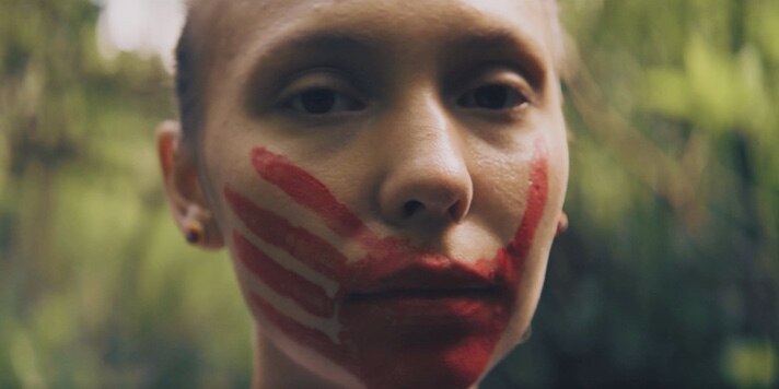 Close up of Roslaie Fisher with a red handprint over her mouth