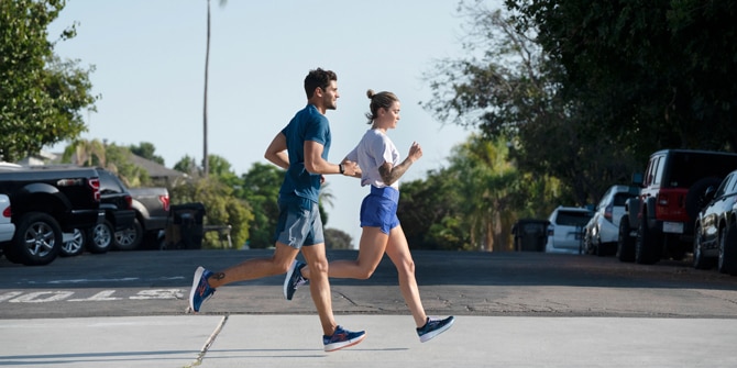 A closeup shot of a runner wearing Brooks Nightlife Collection gear and stooping over to tie his shoes. 