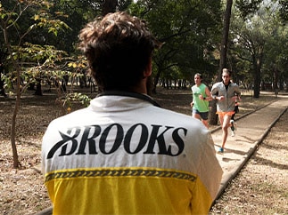 Man in Brooks jacket watching runners