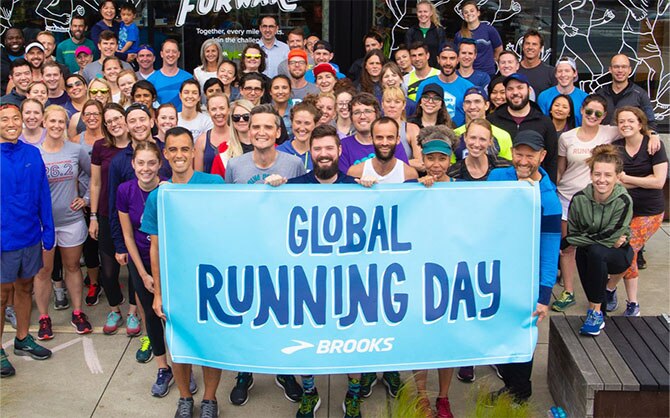 Grupo de empleados de Brooks sujetando una señal que dice "Día mundial del running"