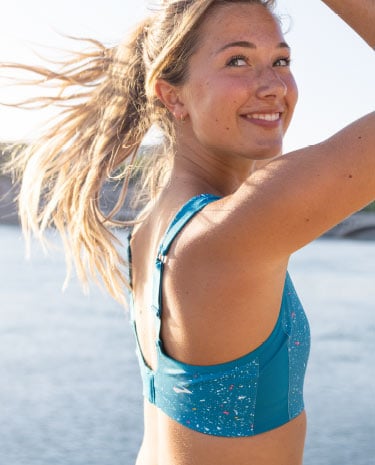 A close-up of a woman in a blue Drive Convertible Run Bra smiling at the camera.