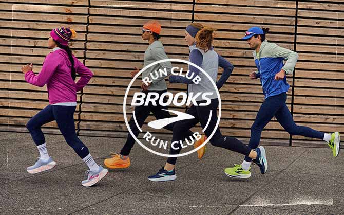 A group of people running on a sidewalk, behind a Brooks Run Club logo