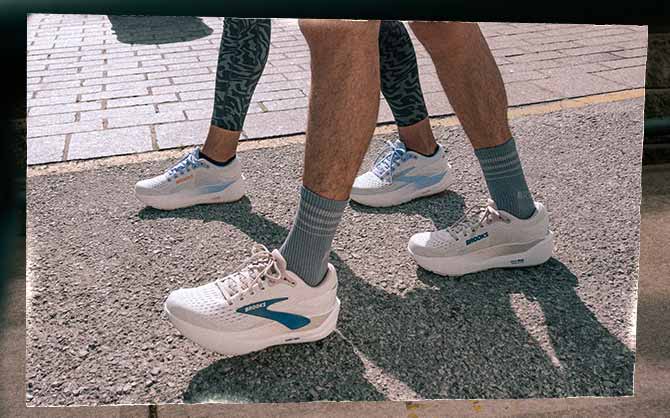 Two people wearing Brooks shoes walk along a sidewalk