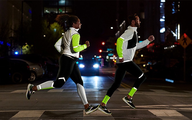 Side view of two runners running in the dark