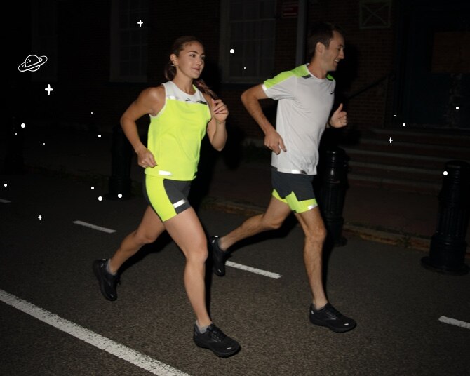 Two runners lit up in reflective gear at night