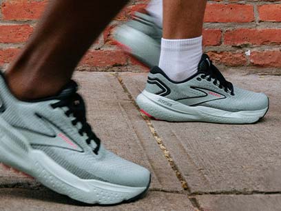 Person wearing gray shoes walking down a sidewalk