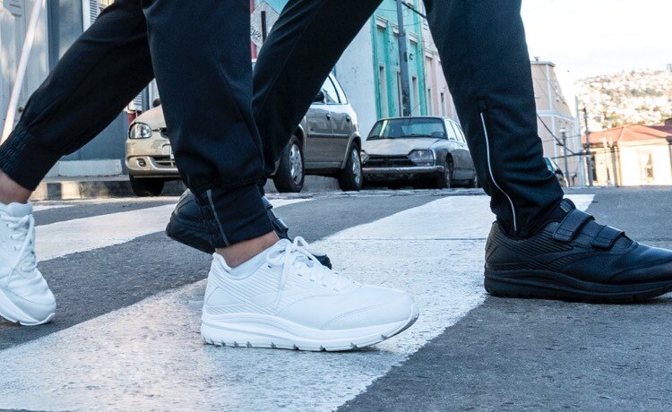 Two people wearing Addiction Walkers crossing the street