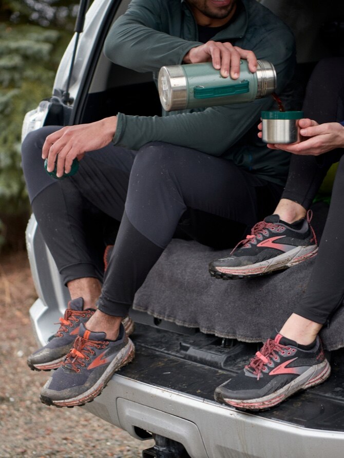 Two runners sitting in the back of a car wearing Cascadia GTX