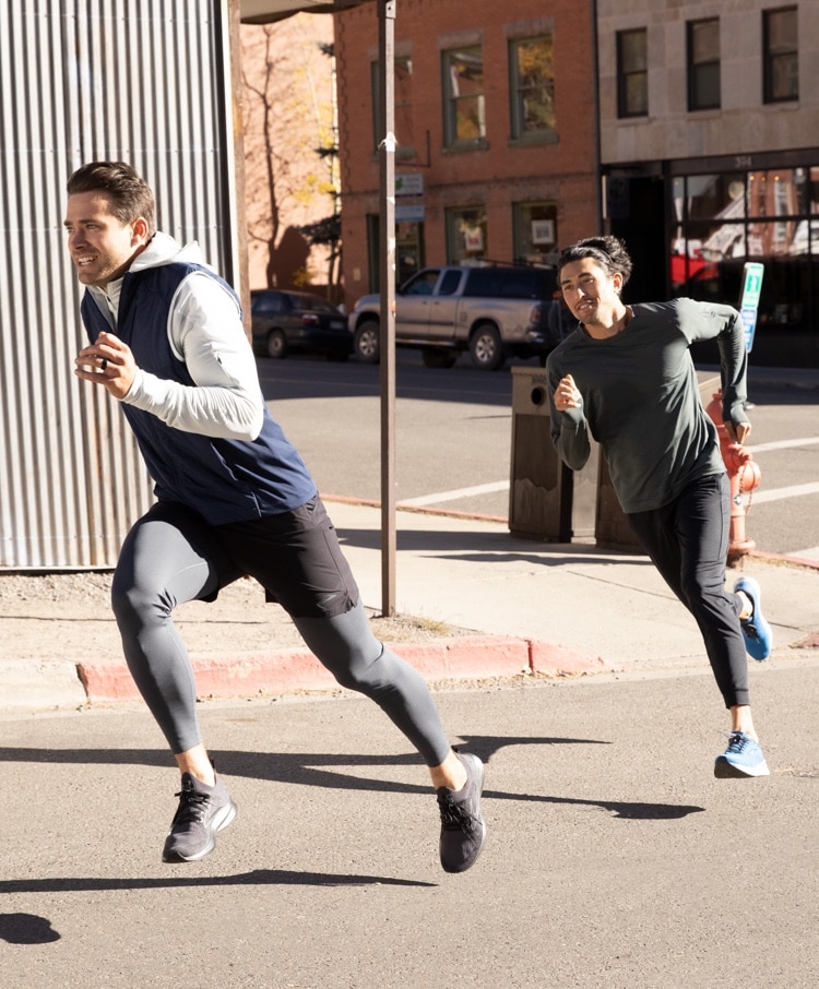 Runners midstride running on a sidewalk