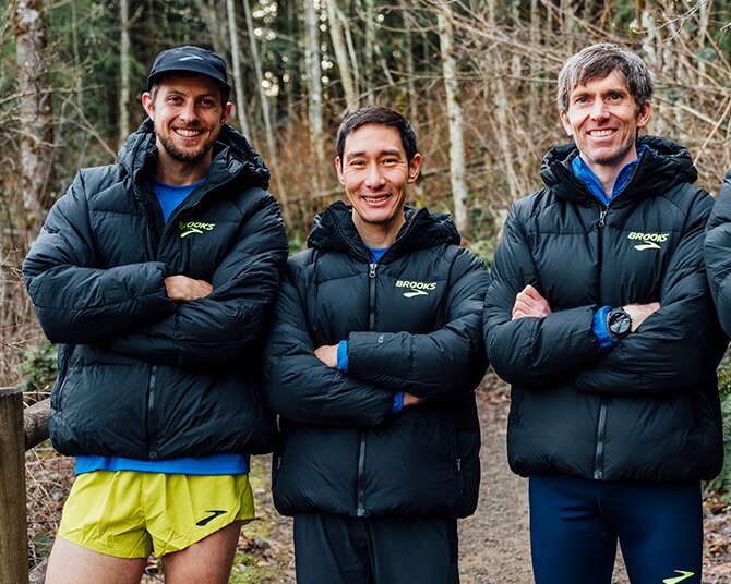 Three runners wearing puffy jackets in a trail