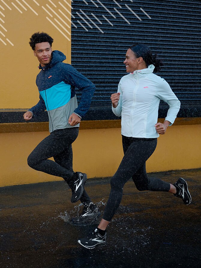 Two runners in the rain, wearing the Canopy Jacket. 