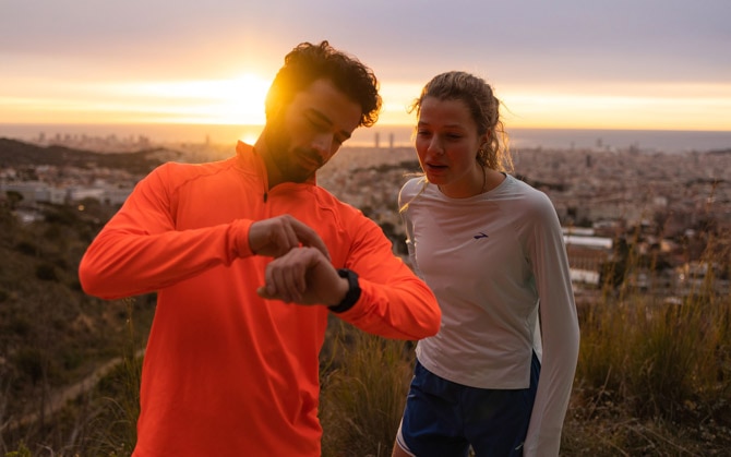 two runners checking a watch during sunset