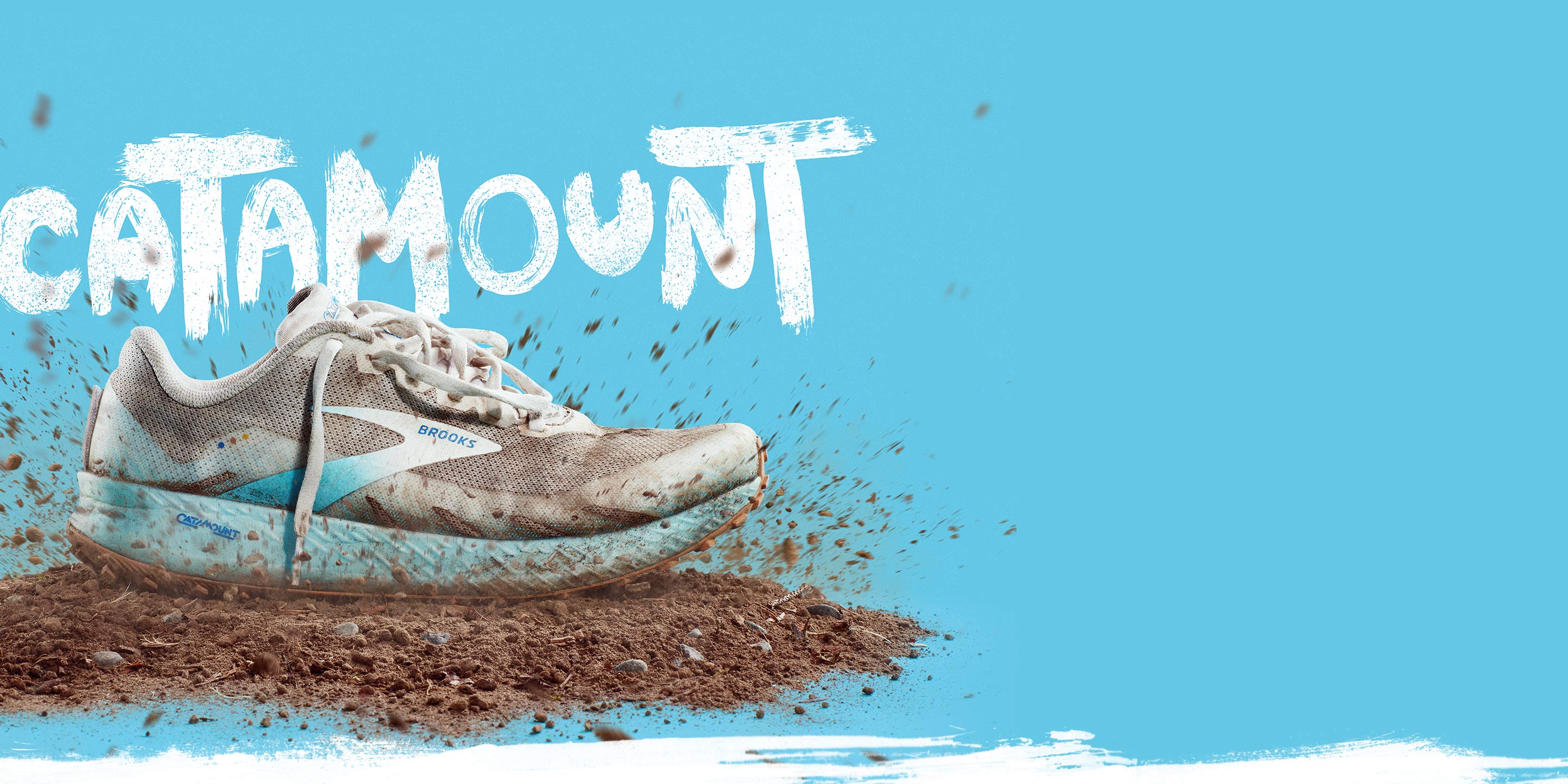 A trail shoe has just fallen on a mound of dirt, surrounded by dirt flying through the air.