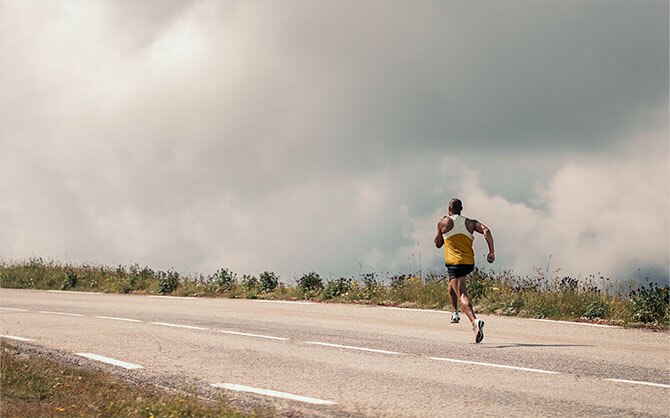 Vista in lontananza di un runner che corre su una strada durante una giornata nuvolosa
