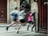 A group of people run on a sidewalk