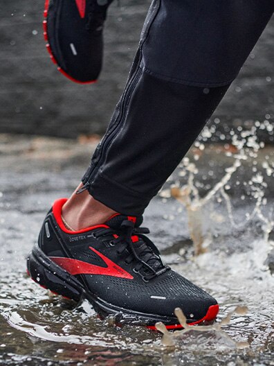 Foot with running shoe splashing in a puddle
